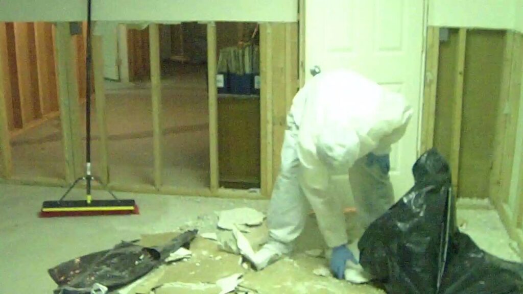 A worker in protective gear removes debris during demolition for water damage restoration by Directed Heat Restoration, Livonia, MI.
