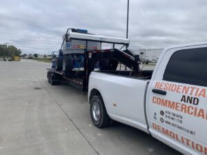 A white pickup truck from Just Take It, LLC. transporting demolition equipment on a trailer in Yorba Linda, CA.