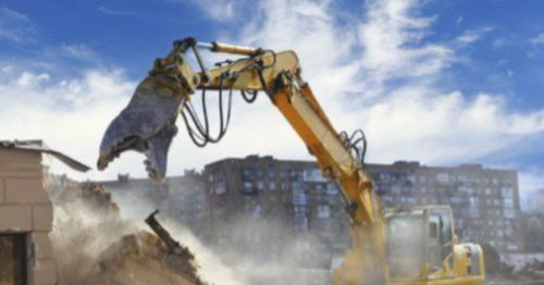 A heavy demolition excavator working on a dusty site, representing DEMO Leaders in Los Angeles, CA