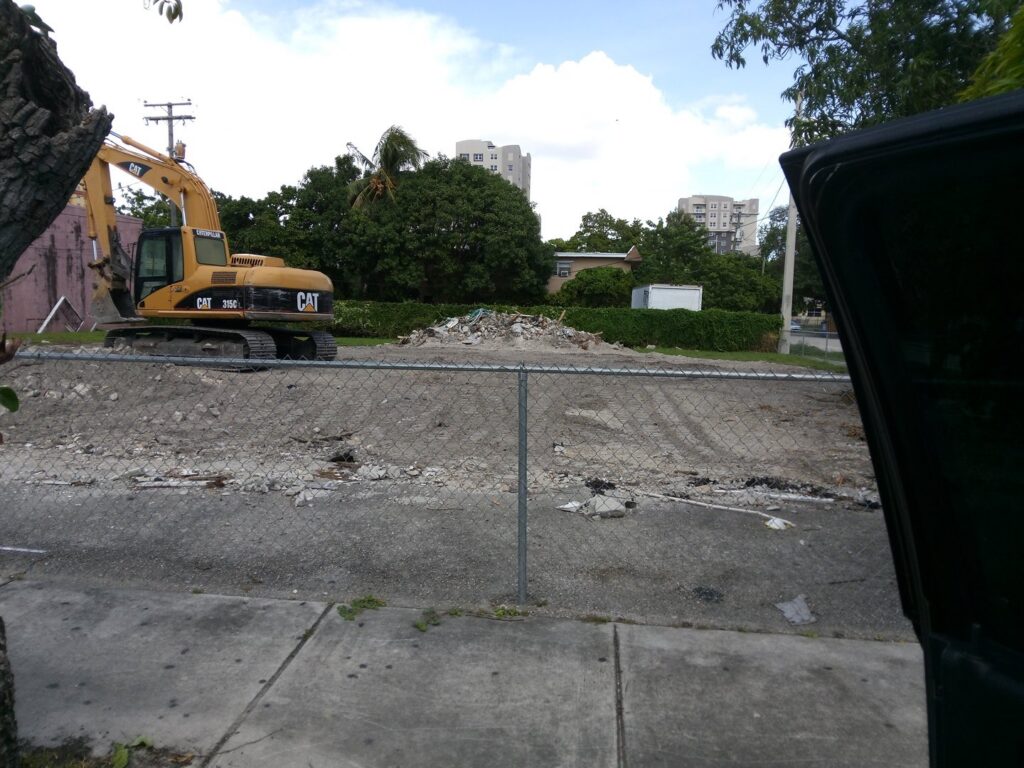 A cleared demolition site with a CAT excavator in the background by Dade Wrecking Demolition LLC in Miami, FL.