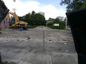 A cleared demolition site with a CAT excavator in the background by Dade Wrecking Demolition LLC in Miami, FL.