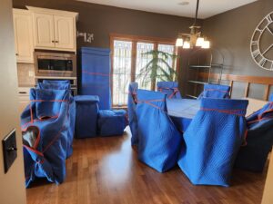 Dining room furniture meticulously wrapped in blue moving blankets by Joy Haul Professional Movers, ready for transport in Columbia City, IN.