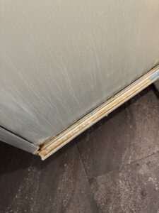 A dirty corner of a kitchen appliance and floor before house cleaning by Grant Cleaning in Missoula, MT.