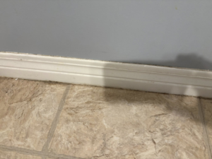 A dusty baseboard and floor before a thorough cleaning service from Sprinkled Clean in Bangor, ME.