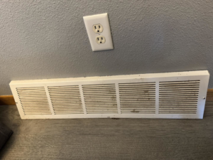 A dirty baseboard heater vent before cleaning by Wicked Clean in Bismarck, ND, showing accumulated dust and grime.