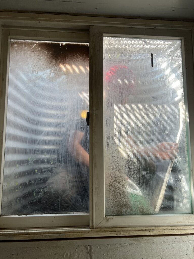 A dirty basement window with visible streaks and grime, illustrating a cleaning challenge for Little Cubs Cleaning Services in Rochester, MN.