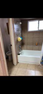 A dirty bathroom with a bathtub and toilet before professional cleaning by Klean Living in Lawson, Dallas, TX.
