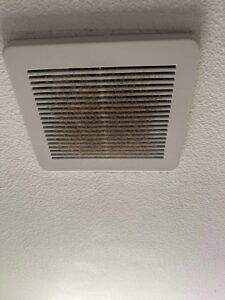 A very dirty bathroom exhaust fan cover before professional cleaning by Nannie Needs LLC in Kent, WA.