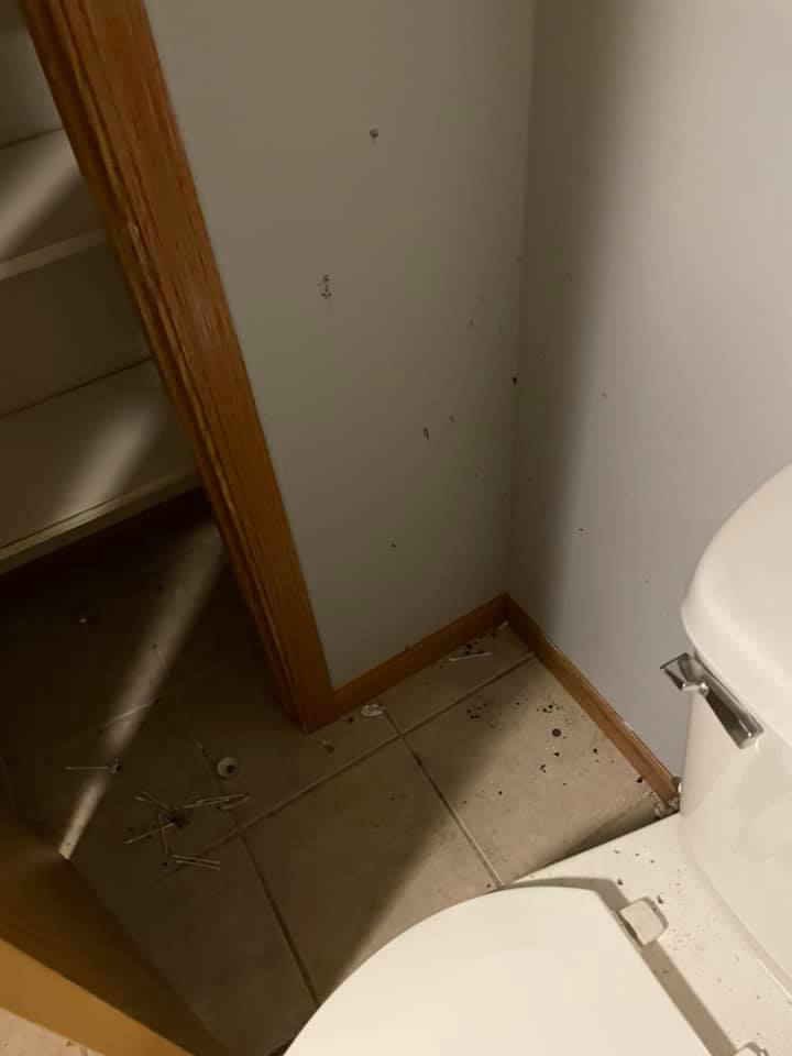 A dirty bathroom floor next to a toilet with debris and dust, showing a 'before' cleaning scenario by Every Time Cleaning in Cedar Rapids, IA.