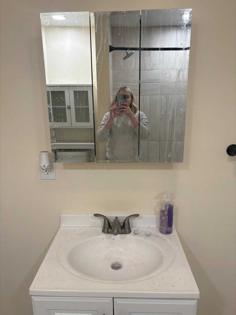 A dirty bathroom mirror with streaks and a dirty sink before cleaning by Tri-State Clean Queen in Elsmere, KY.