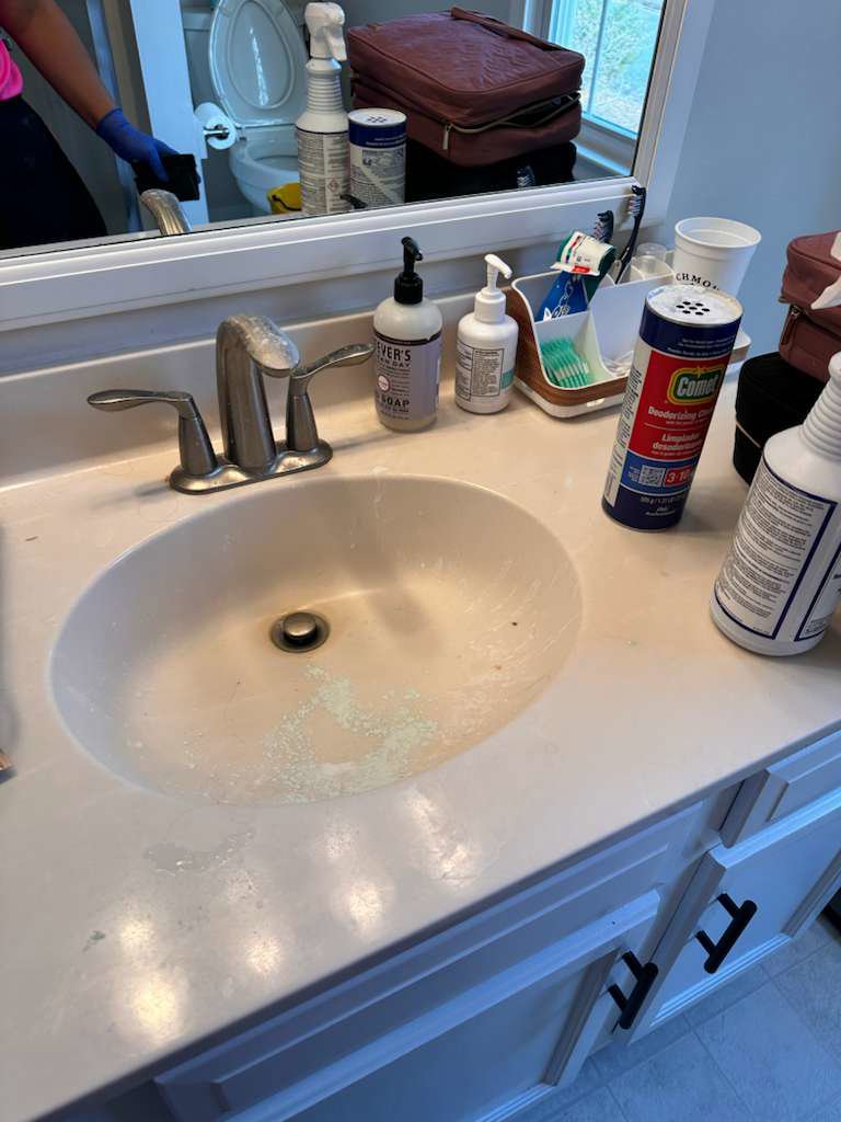 A dirty bathroom sink with cleaning supplies on the counter, ready for cleaning by New Image Cleaning Service LLC in Richmond, VA.