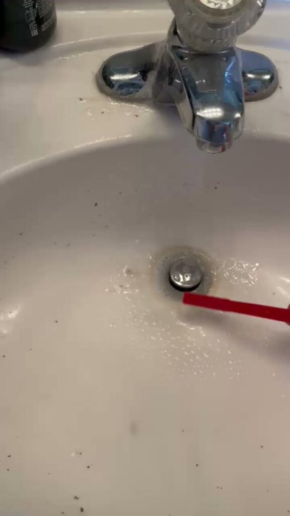 A dirty bathroom sink with visible debris and a toothbrush, showing a "before" cleaning state by Picky Performance Cleaning in North Las Vegas, NV
