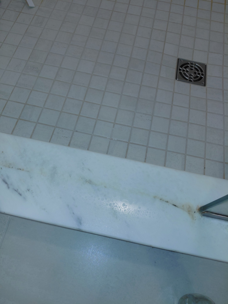 Dirty bathroom tiles and a stained marble surface, illustrating areas cleaned by White Lotus Cleaning Services LLC in Nashua, NH.