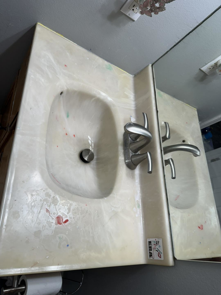 A dirty bathroom vanity and sink with colored spots before cleaning by Lake Area Cleaning Services in Lake Charles, LA