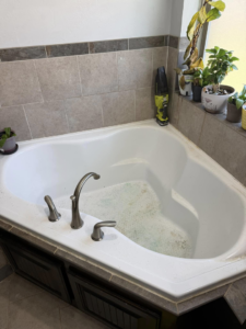 A dirty bathtub with green residue, showing a before-cleaning state by Hey Sis Cleaning LLC in Edmond, OK.