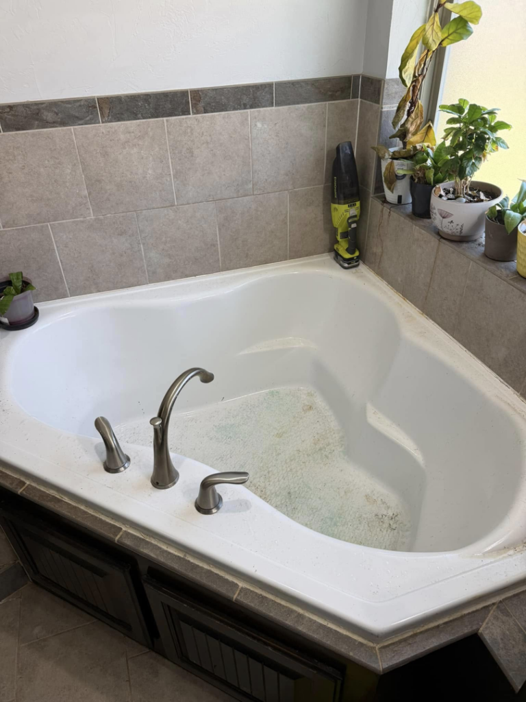 A dirty bathtub with green residue, showing a before-cleaning state by Hey Sis Cleaning LLC in Edmond, OK.