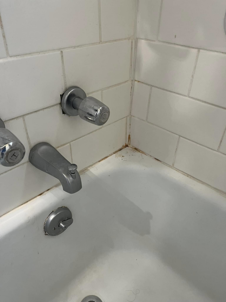 A dirty bathtub corner showing grime and mildew, before cleaning by Shine Bright Cleaning Co. in Overland Park, KS.