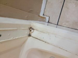 A dirty bathtub corner showing mold and grime buildup, indicating a need for thorough bathroom cleaning from Sparkle & Shine of Iowa in Urbandale, IA.