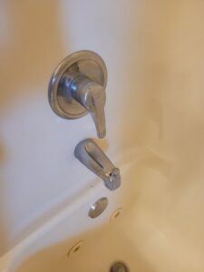A dirty bathtub faucet and surrounding wall before cleaning by Ady's Housekeeping in Yakima, WA