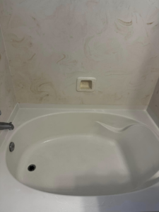 A dirty bathtub and shower wall showing grime, indicating the need for professional cleaning services from The Kleenerz in Tucson, AZ.