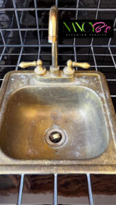 A dirty brass sink with hard water stains and grime before cleaning by Nancy B's Cleaning Service LLC in Atlanta, GA.