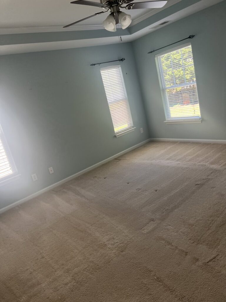 A bedroom with a dirty carpet showing visible stains, indicating a need for professional house cleaning by Royal Madam Cleaning LLC in Charlotte, NC.