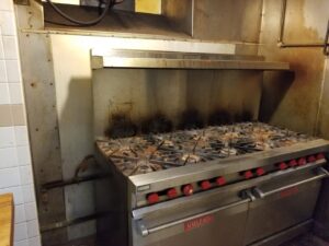 A dirty commercial kitchen stove and range before professional cleaning by Cooper-N-Folks in Philadelphia, PA