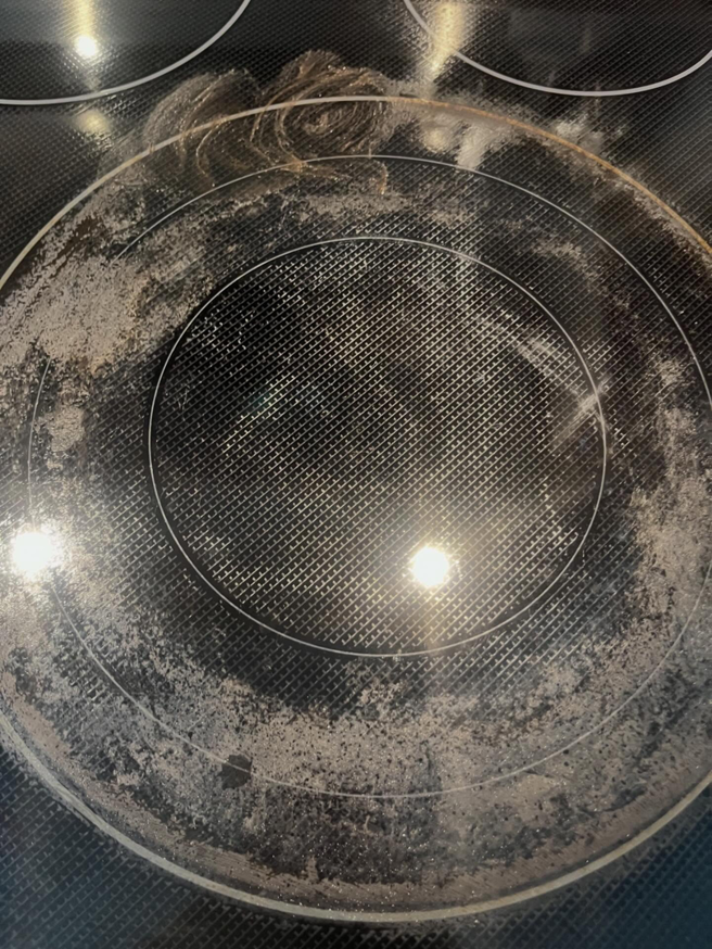 A heavily soiled electric stovetop with burnt-on residue, before professional cleaning by BLACK PEARL Cleaning CO. in Greenwood, MO.