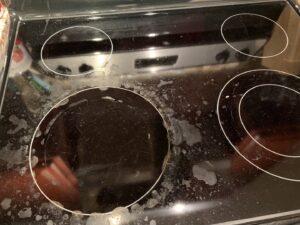 A close-up of a dirty electric stovetop with visible grime and residue, before cleaning by Jolley Services, INC in Bossier City, LA.