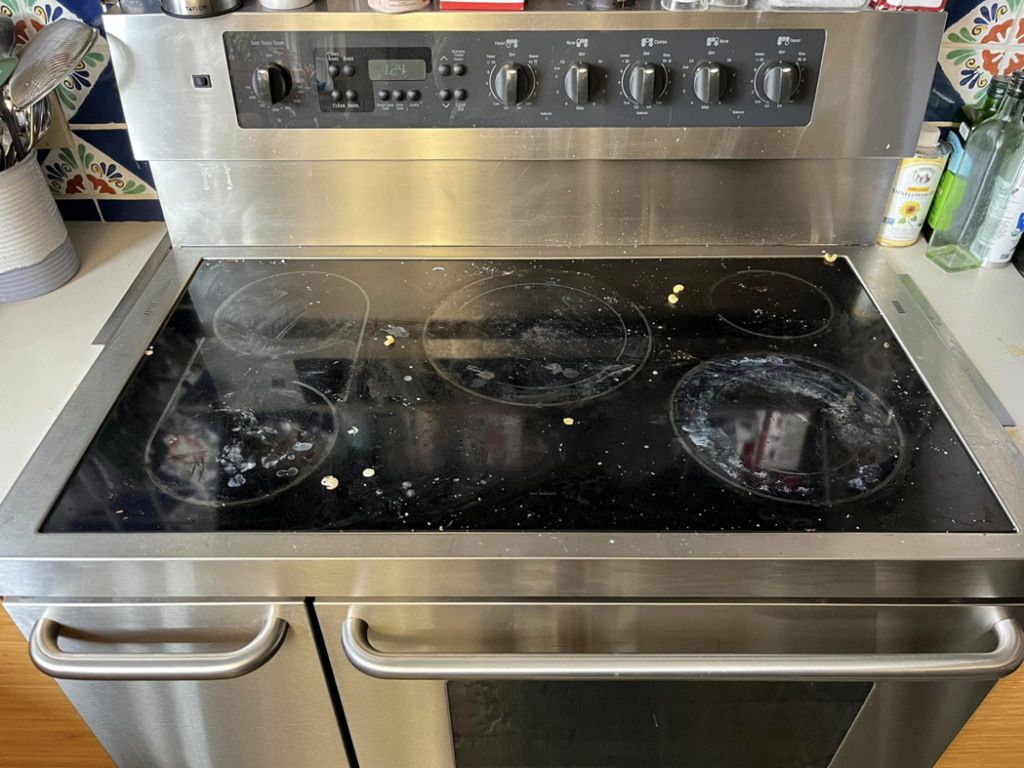 A dirty electric stovetop with food spills before cleaning by Lorena Lyons Cleaning in Concord, NH.