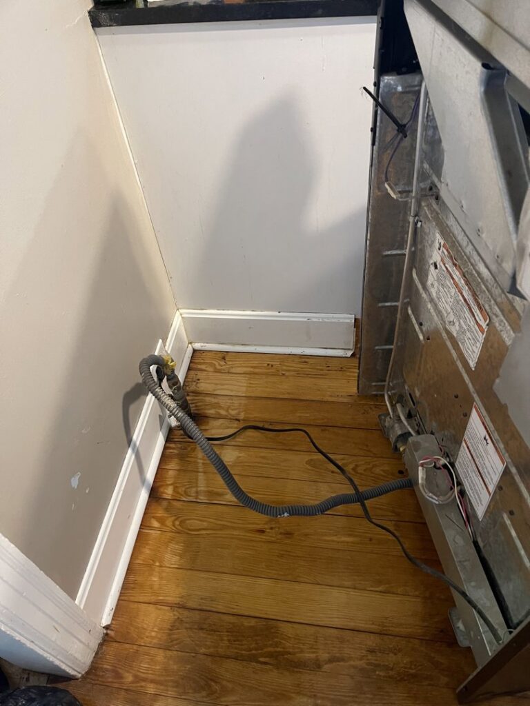 A dirty floor area with debris and wires behind an appliance, showing a space needing deep cleaning by JLJ Sister's Cleaning & More in Lexington, KY.