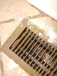 A dirty floor vent covered in dust and debris, showing an area ready for deep cleaning by Maid to Serve HIM in Cincinnati, OH.