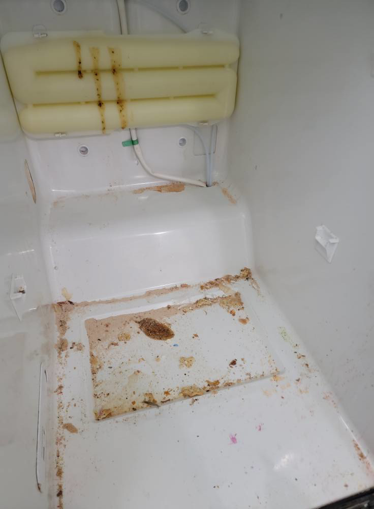 A dirty freezer interior with food debris and spills before professional cleaning by Windham Cleaning in Akron, OH.