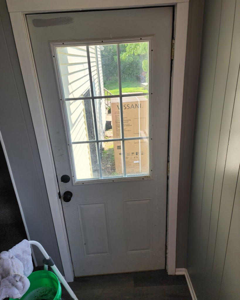 A dirty glass door with cleaning supplies nearby, indicating a cleaning project for Christina's Tidy Homes in Canton, OH.