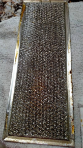 A dirty and greasy range hood filter, ready for a thorough cleaning by Maid It Dirty Cleaning Company in Phoenix, AZ.