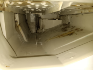 A dirty ice maker compartment with grime and mold, requiring deep cleaning from KB Cleaning in Bozeman, MT.
