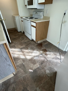 A dirty kitchen floor with spills and debris, ready for a thorough cleaning by E & S Cleaning Services L.L.C in Nampa, ID.