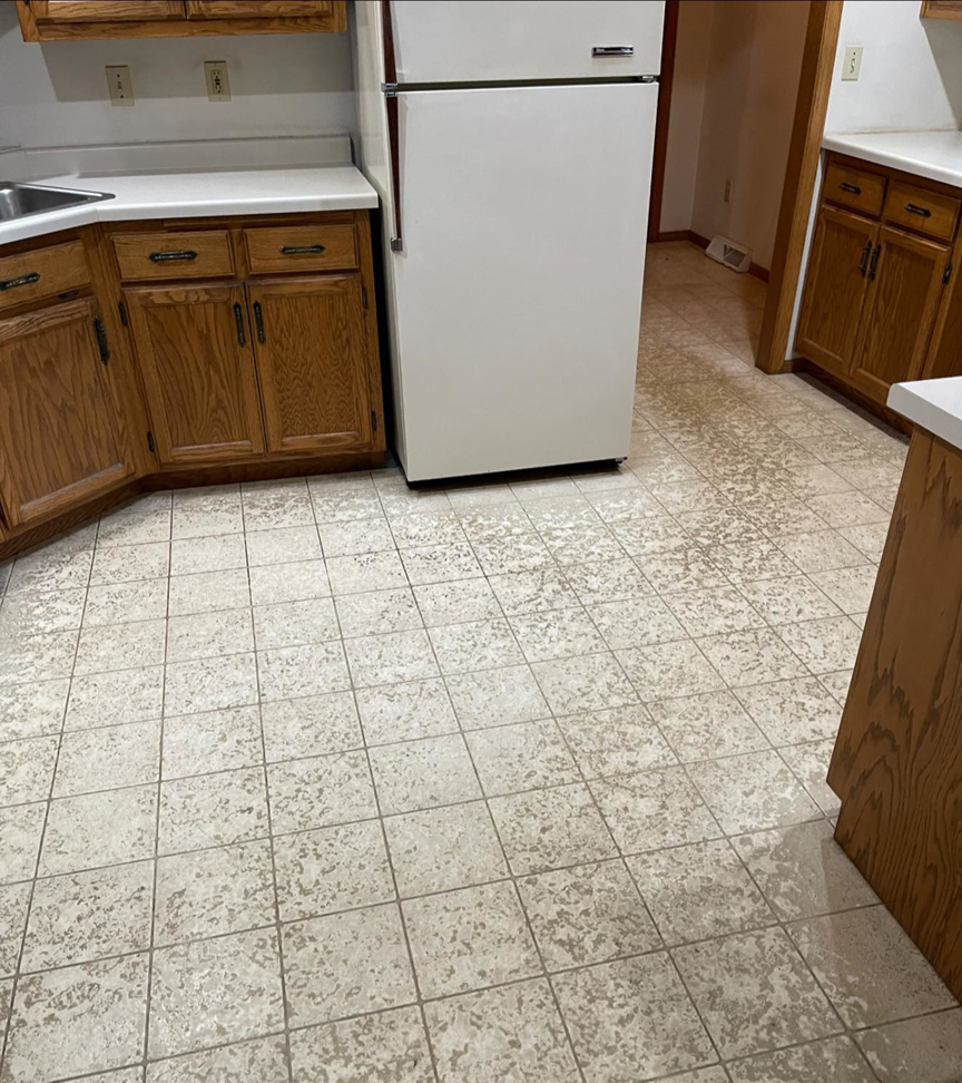 A dirty kitchen floor with worn tiles before cleaning by Trust-Clean in Green Bay, WI.