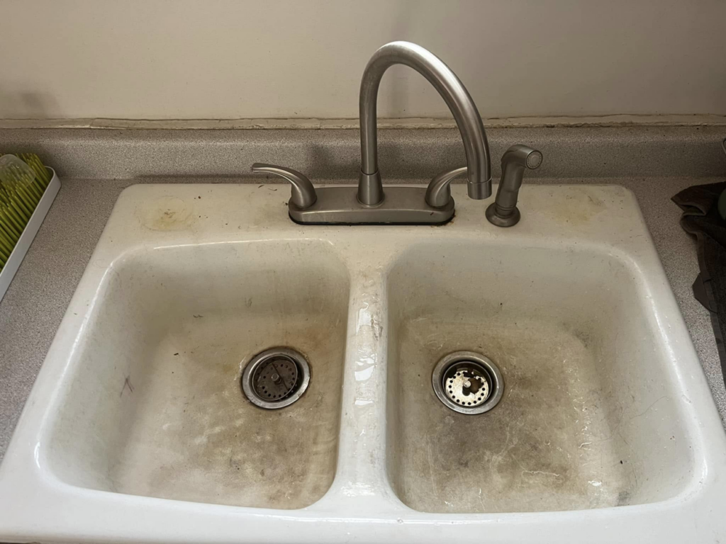 A dirty double kitchen sink before professional cleaning by Lorena Lyons Cleaning in Concord, NH.