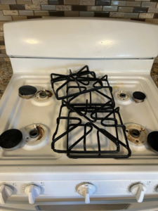 A dirty kitchen stovetop with grates before professional cleaning by Superior Quality Cleaners in Sacramento, CA