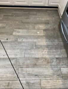 A dirty kitchen tile floor showing grime and debris before professional cleaning by Cuse Cleaning in Syracuse, NY.