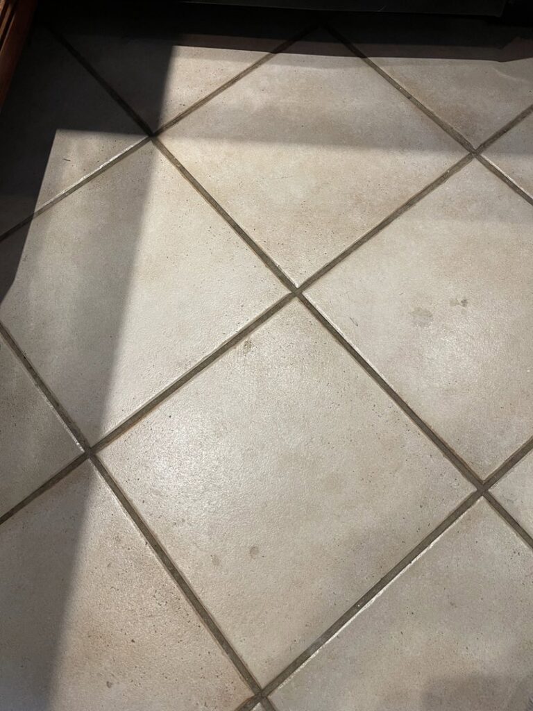A dirty kitchen tile floor with visible grime and spots, indicating a need for professional cleaning from JLJ Sister's Cleaning & More in Lexington, KY.