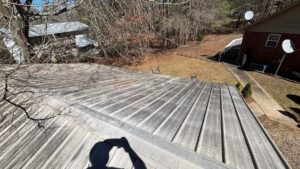 A dirty metal roof covered in grime and streaks before professional cleaning by Plains Power Washing in Auburn, AL.
