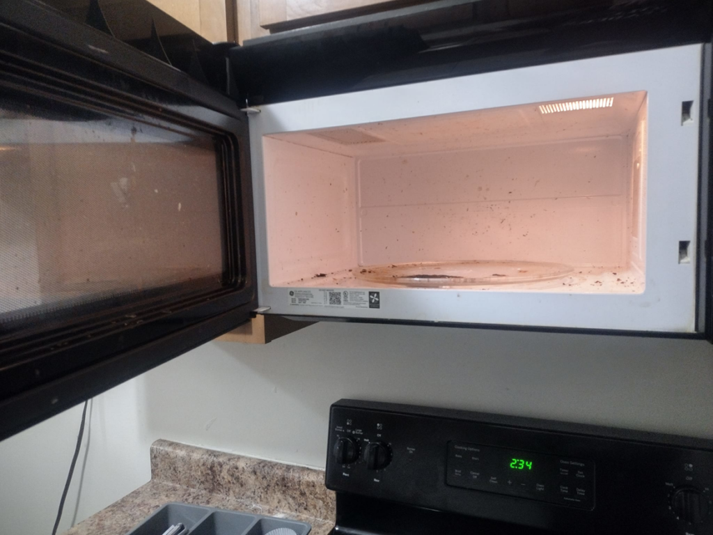 A dirty microwave interior with food splatters, showing the need for cleaning by By Grace Cleaning Solutions, LLC in Cincinnati, OH.