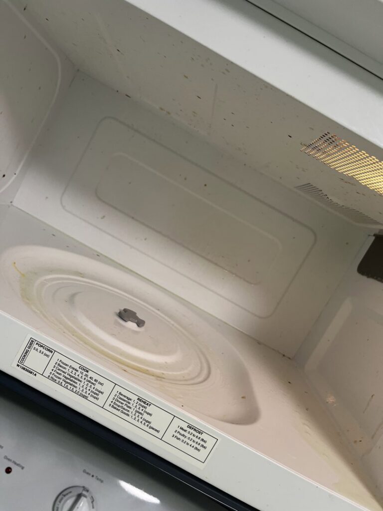 A dirty microwave interior with visible food splatters, indicating a cleaning task for Final Touch & More in Fort Wayne, IN