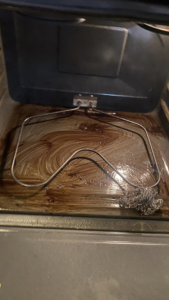 A very dirty oven interior with a scrubbing pad, showing a challenging cleaning task handled by Estela's Cleaning Service's in Lake Elmo, MN.