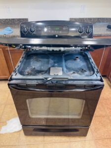 A dirty oven with the top lifted, showing grime before cleaning by JLJ Sister's Cleaning & More in Lexington, KY.