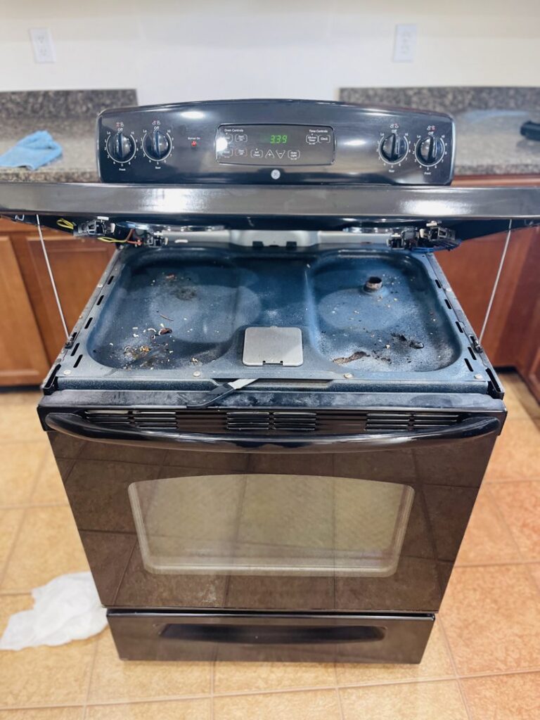 A dirty oven with the top lifted, showing grime before cleaning by JLJ Sister's Cleaning & More in Lexington, KY.