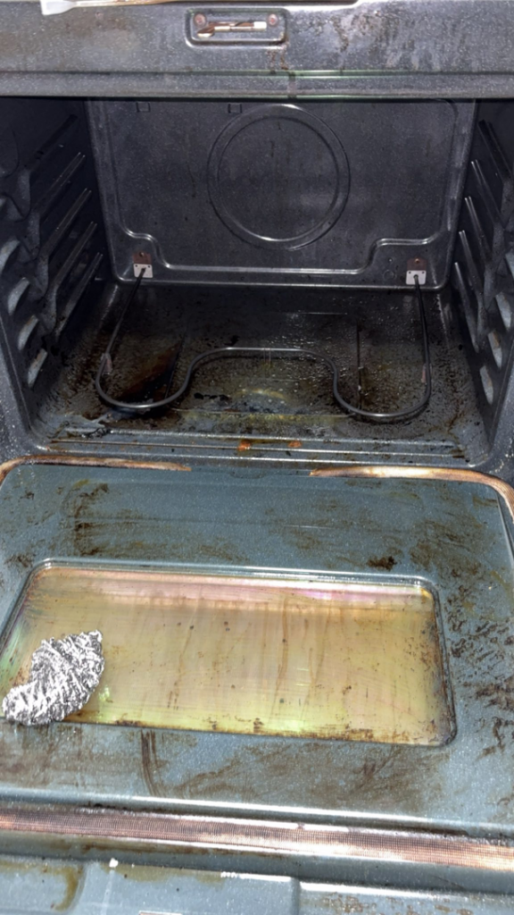 A very dirty oven interior with a scrubbing pad, showing a before-cleaning state by Down And Dirty Cleaning in Clayton, NC.