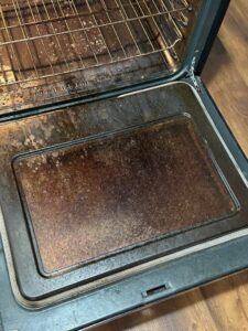 A dirty oven interior with greasy racks and burnt residue before deep cleaning by Teri Lynn's Cleaning in Williston, ND.
